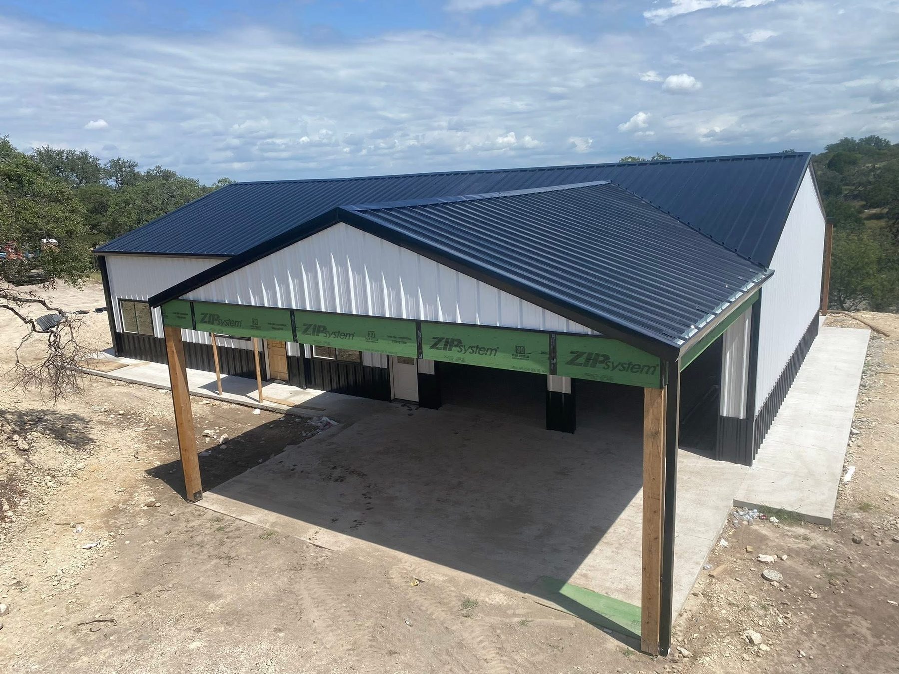 White and black barndominium shell with metal roof and covered porch